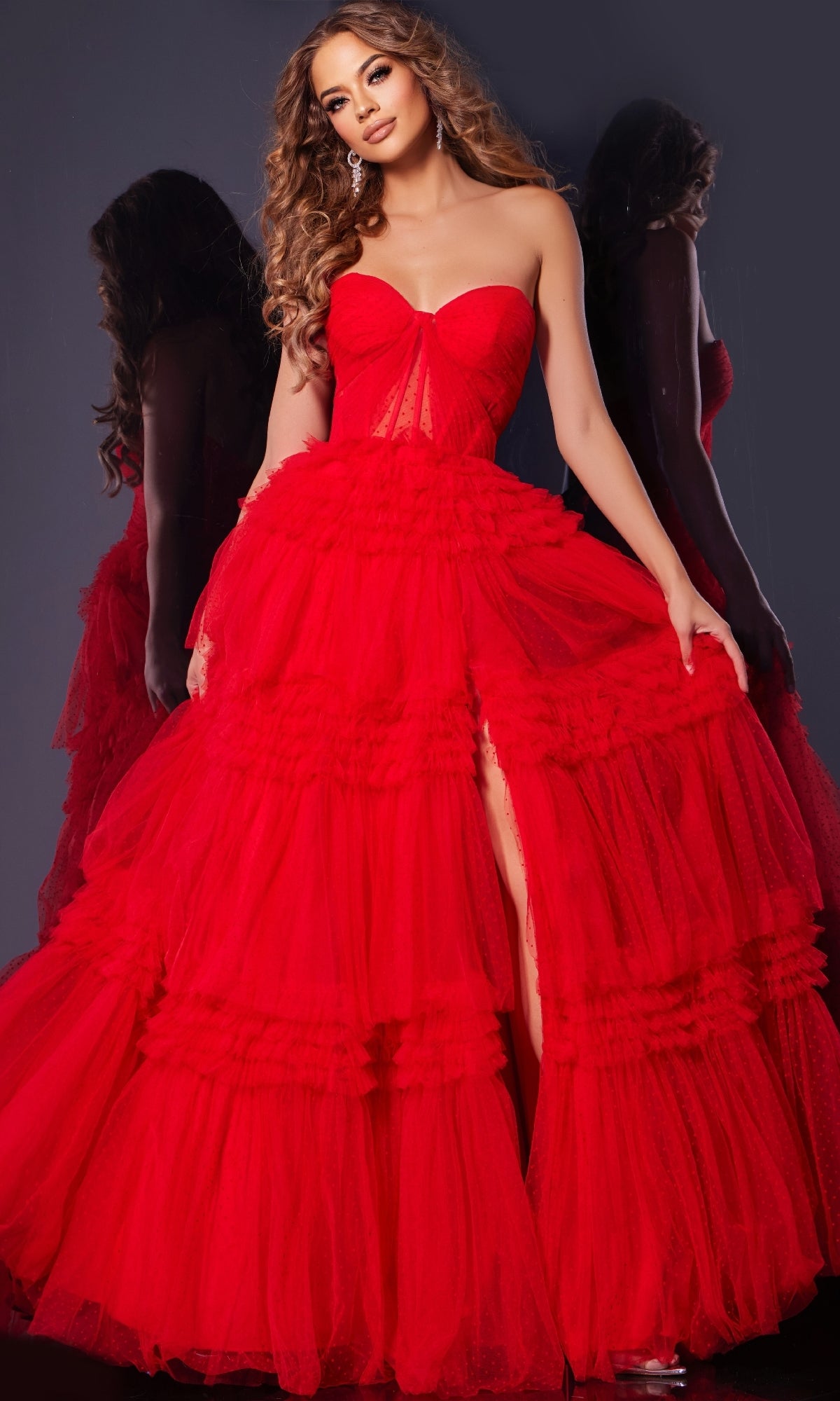 A woman wears the Jovani 40466 strapless prom ball gown with a corset bodice, sweetheart neckline, and layered tulle skirt, standing before a mirror on a dark background with her reflection visible.